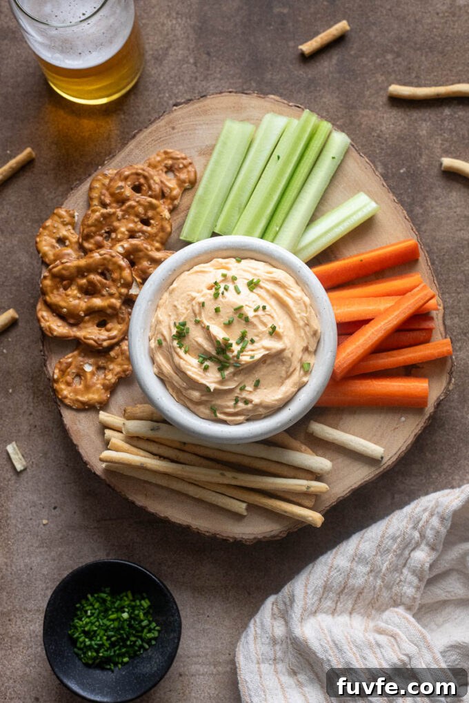 White cheddar pub cheese on a board with veggies and pretzels.