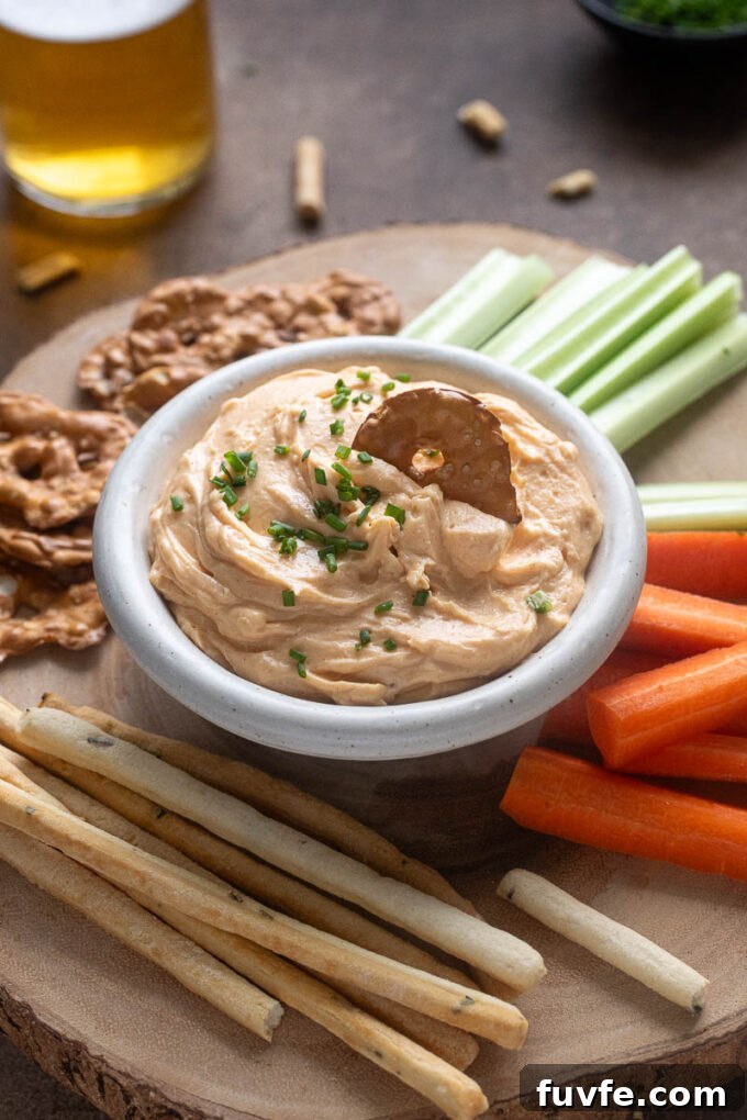 White cheddar pub cheese in a bowl with pretzel dipped in.