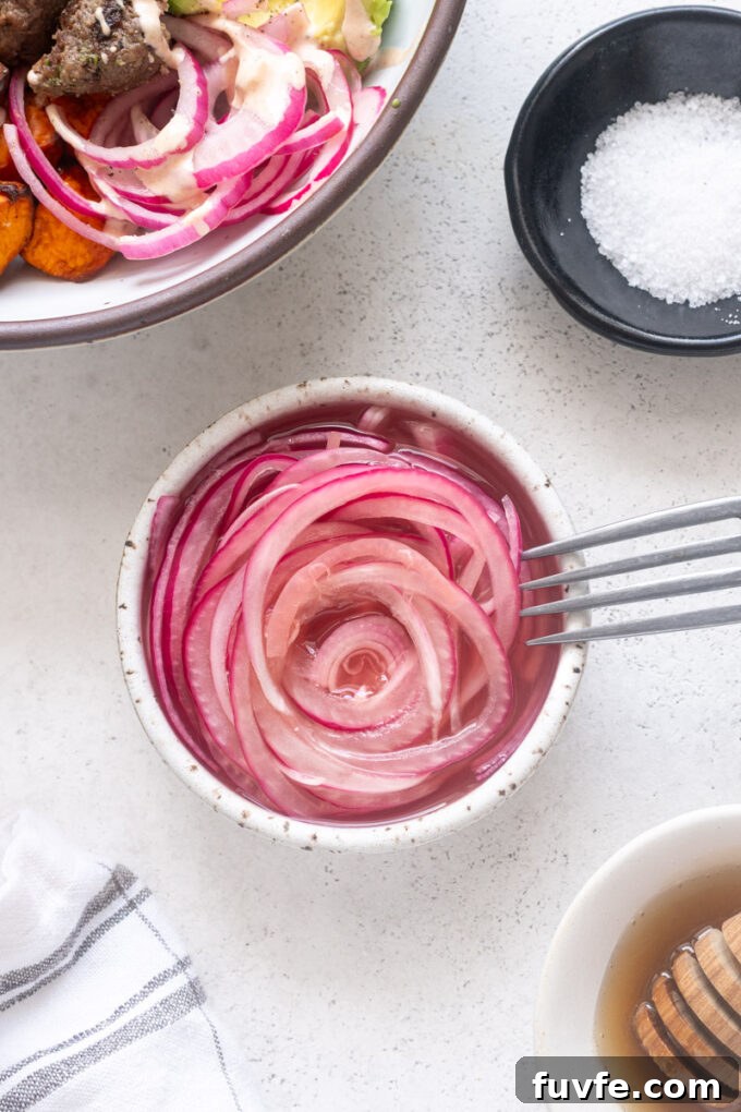 Quick pickled red onions in a small bowl with fork.