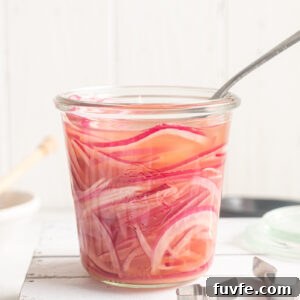 Quick pickled red onions in a jar with a fork buried in it.