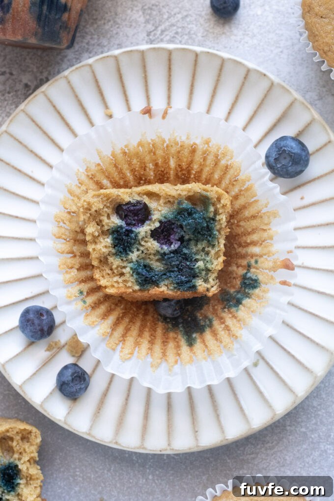 Blueberry oat flour muffin on a plate cut in half to expose tender crumb.