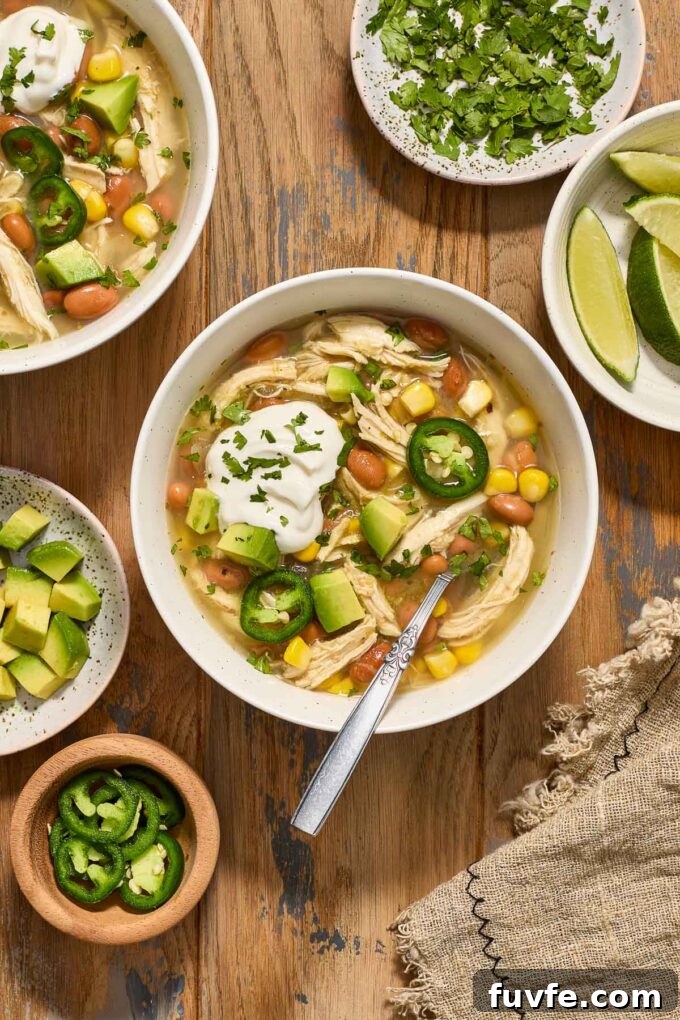 Green chicken enchilada soup in a bowl with sour cream and cilantro.