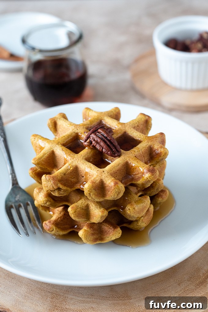Stack of sweet potato waffles with pecans and maple syrup