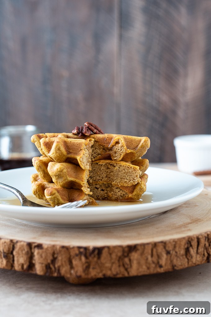 Stack of sweet potato waffles cut with syrup dripping down