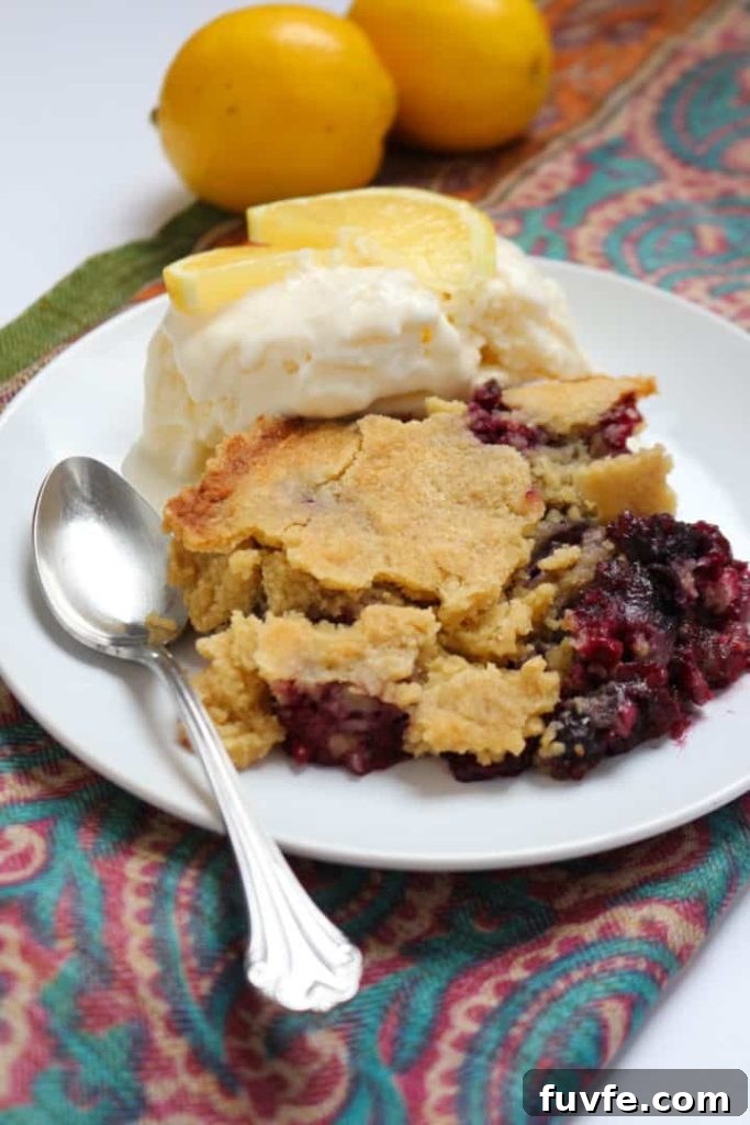 A slice of gluten-free berry cake on a white plate with ice cream and lemon slices