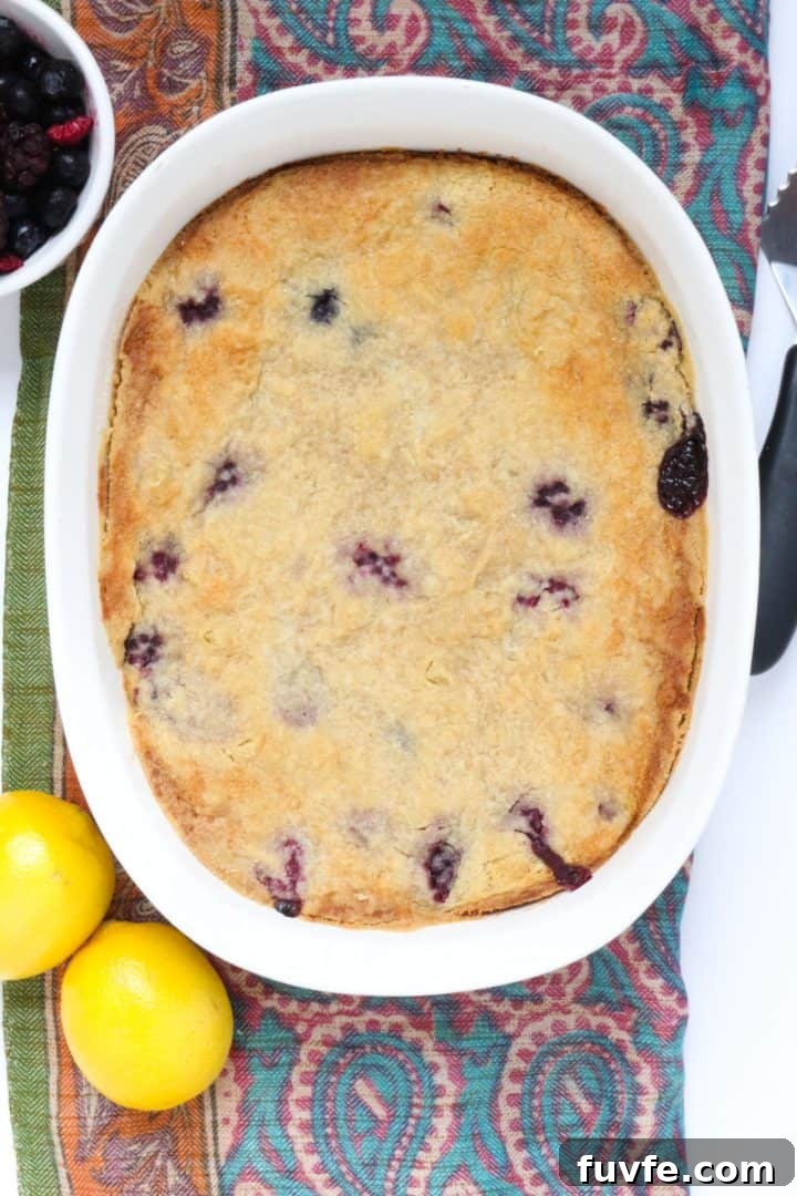 Gluten-Free dump cake in white baking dish with berries and lemons beside it