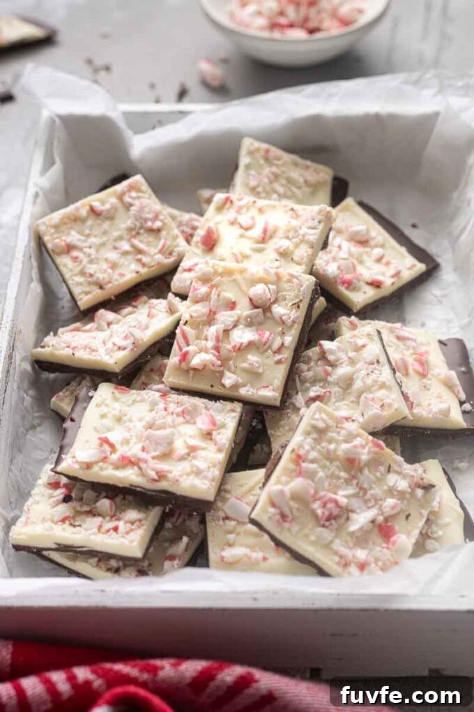 Peppermint bark squares stacked on each other in a serving box.