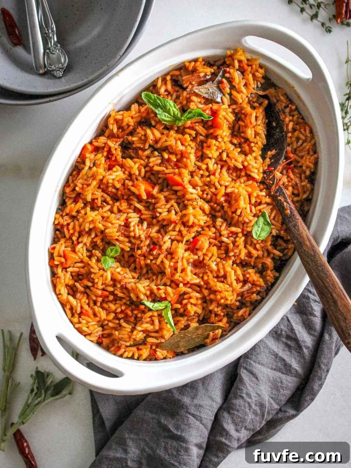 Smoky Nigerian Jollof Rice Recipe – Authentic West African Flavor 3 party jollof served in a white ceramic server garnished with basil.