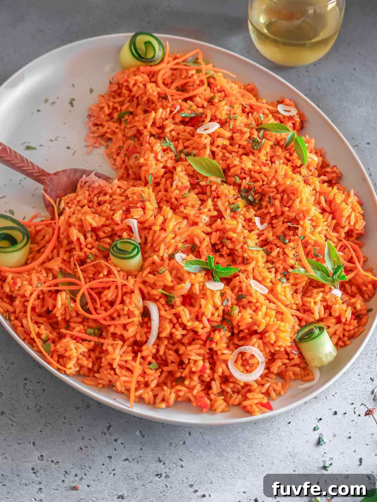 Smoky Nigerian Jollof Rice Recipe – Authentic West African Flavor 7 rice on a gray plate served with a drink.