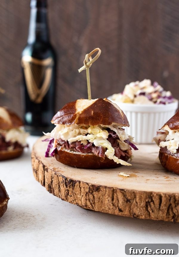 Reuben Style Corned Beef Sliders with Swiss and Sauerkraut 2 guinness corned beef sliders on serving platter with coleslaw alongside