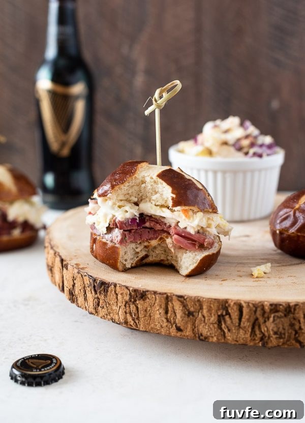 Reuben Style Corned Beef Sliders with Swiss and Sauerkraut 3 Guinness corned beef sliders on serving platter with a bite out of front slider
