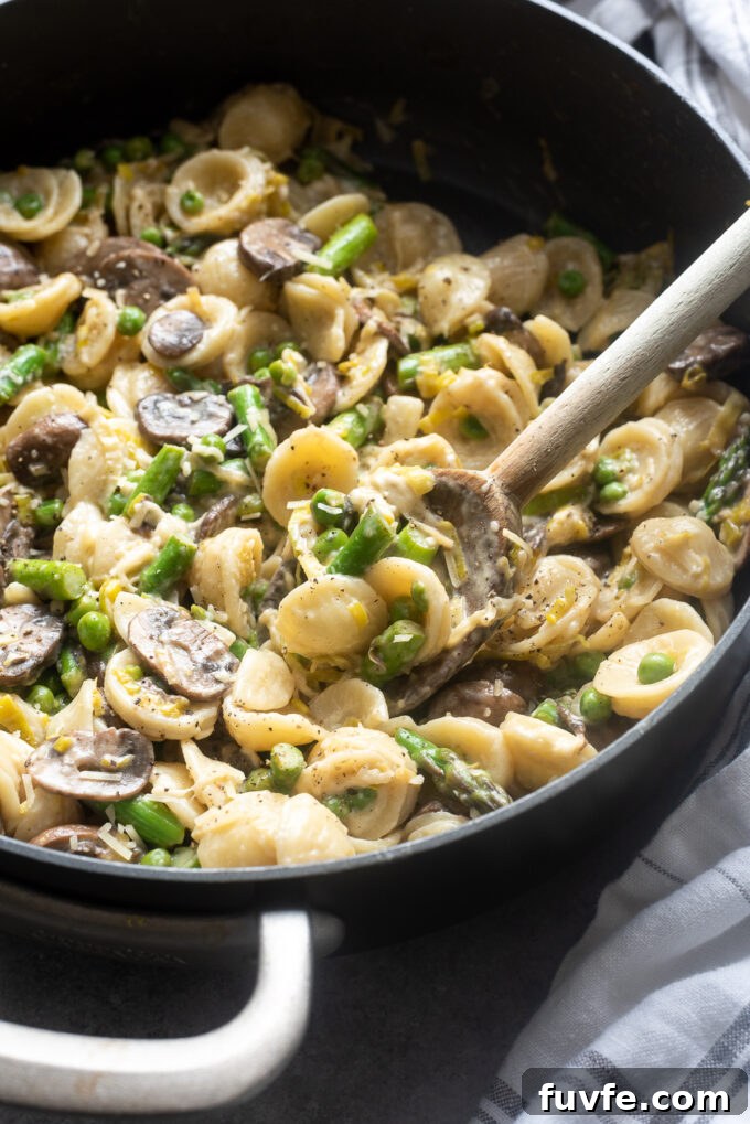 One-Pot Spring Primavera Pasta 8 One pot creamy vegetable pasta in a skillet with wooden spoon.