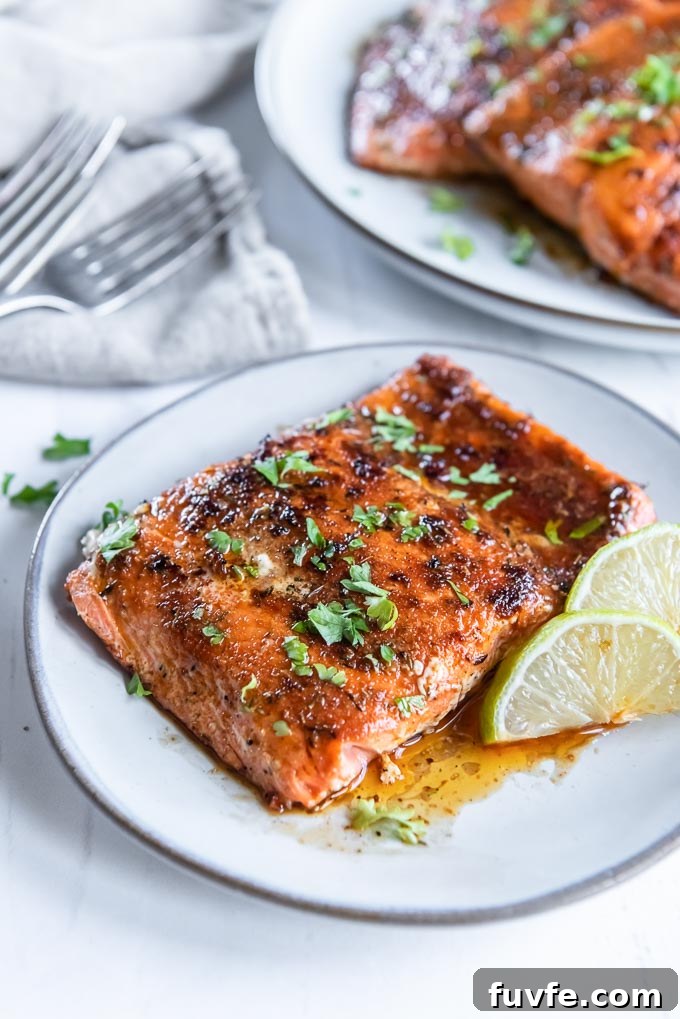 Blackened Salmon with Cajun Spice and Lemon Butter 7 Blackened salmon filet on a white plate with parsley and lime