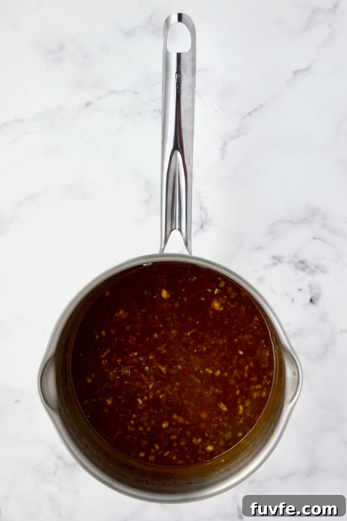 Asian-Style Turkey Meatballs with Ginger-Soy Glaze 11 Ingredients for sauce for meatballs in stainless steel saucepan after being simmered and thickened.