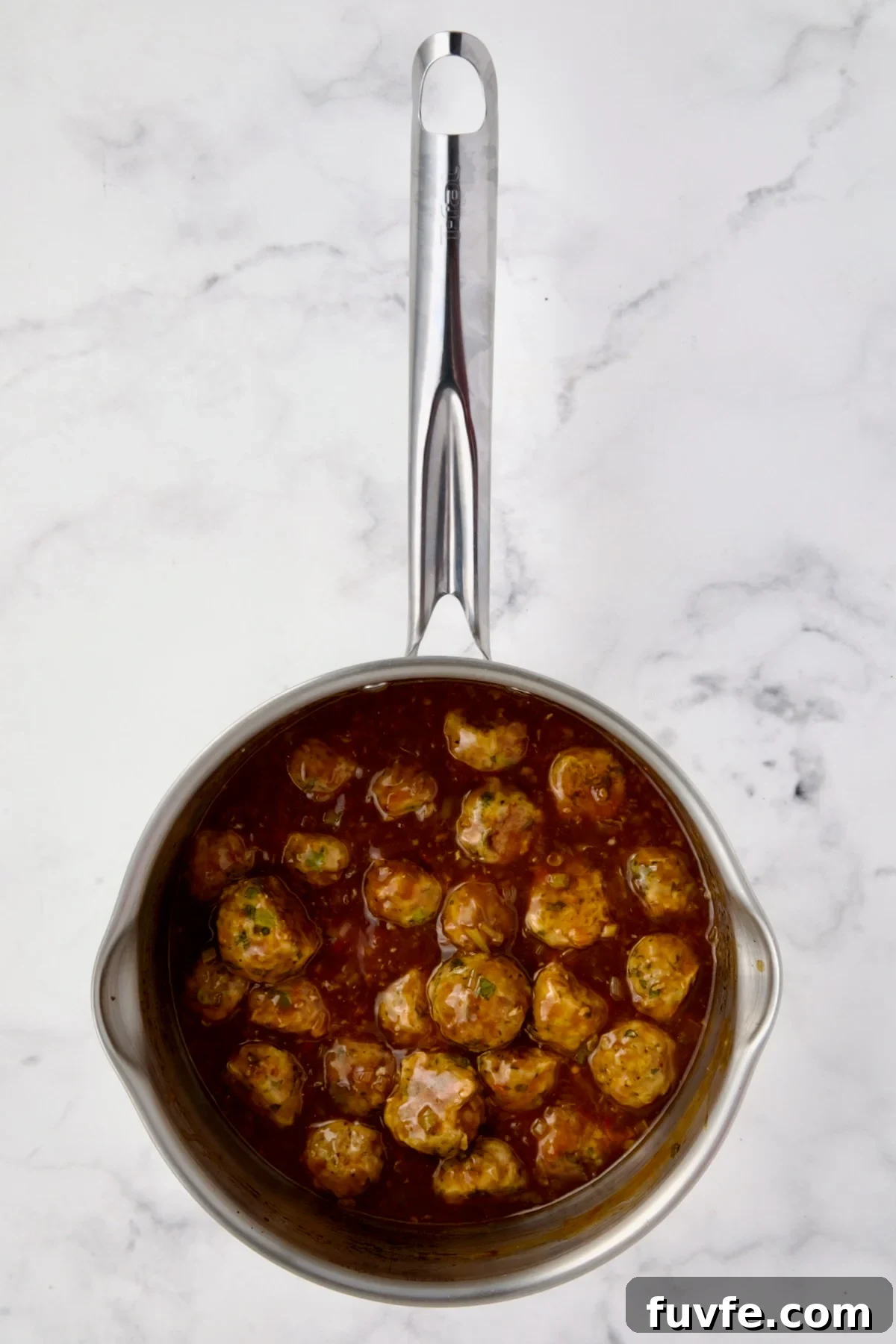 Asian-Style Turkey Meatballs with Ginger-Soy Glaze 12 Meatballs and sauce in stainless steel saucepan.