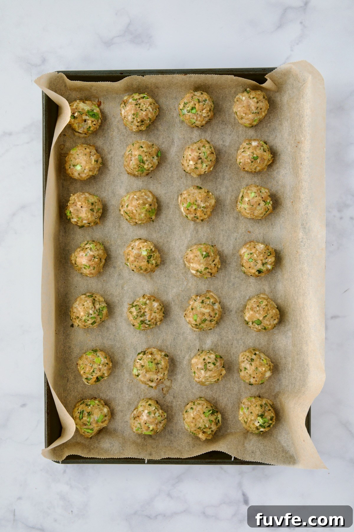 Asian-Style Turkey Meatballs with Ginger-Soy Glaze 9 Turkey meatballs on parchment paper lined baking sheet after being baked.