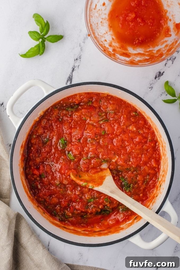 Easy marinara sauce in a white Dutch oven with wooden spoon