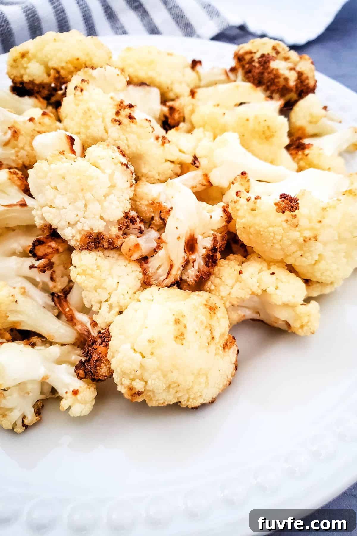 Crispy Air-Fried Cauliflower Recipes for Every Meal 2 A plate of air fryer fried cauliflower florets on a white dish, showing slightly browned edges.