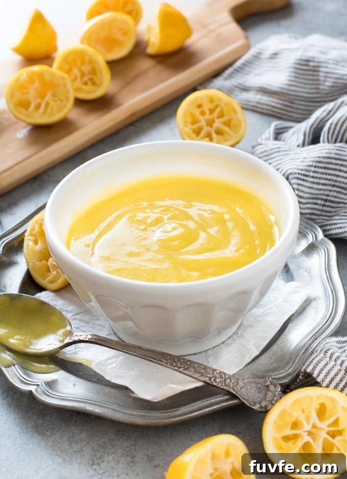 Homemade lemon curd in a bowl with juiced lemons all around