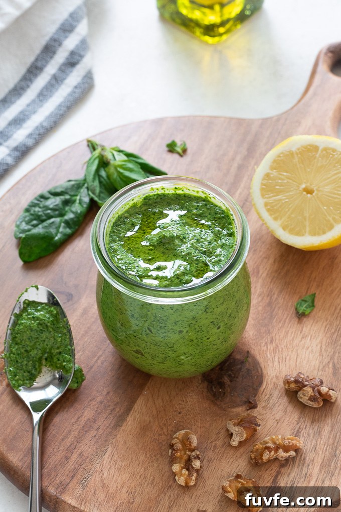 Spinach walnut pesto in a jar with a spoon alongside