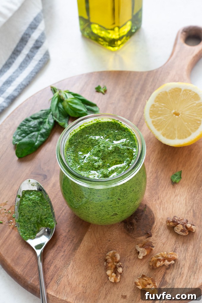 Spinach pesto in a jar with lemon, walnuts and basil alongside
