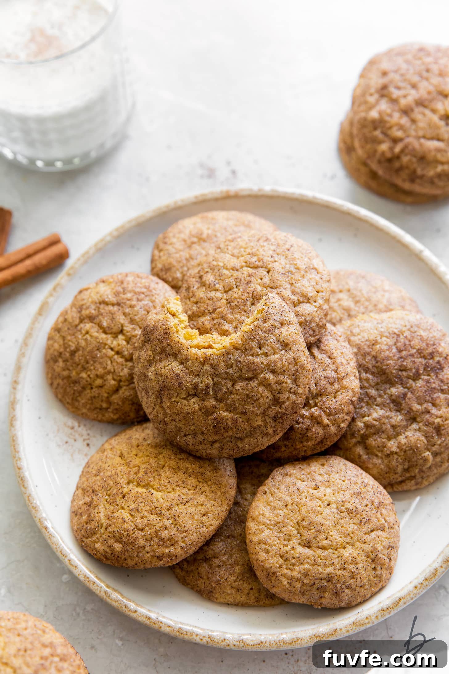 pumpkin snickerdoodles on white plate and top cookie with a bite