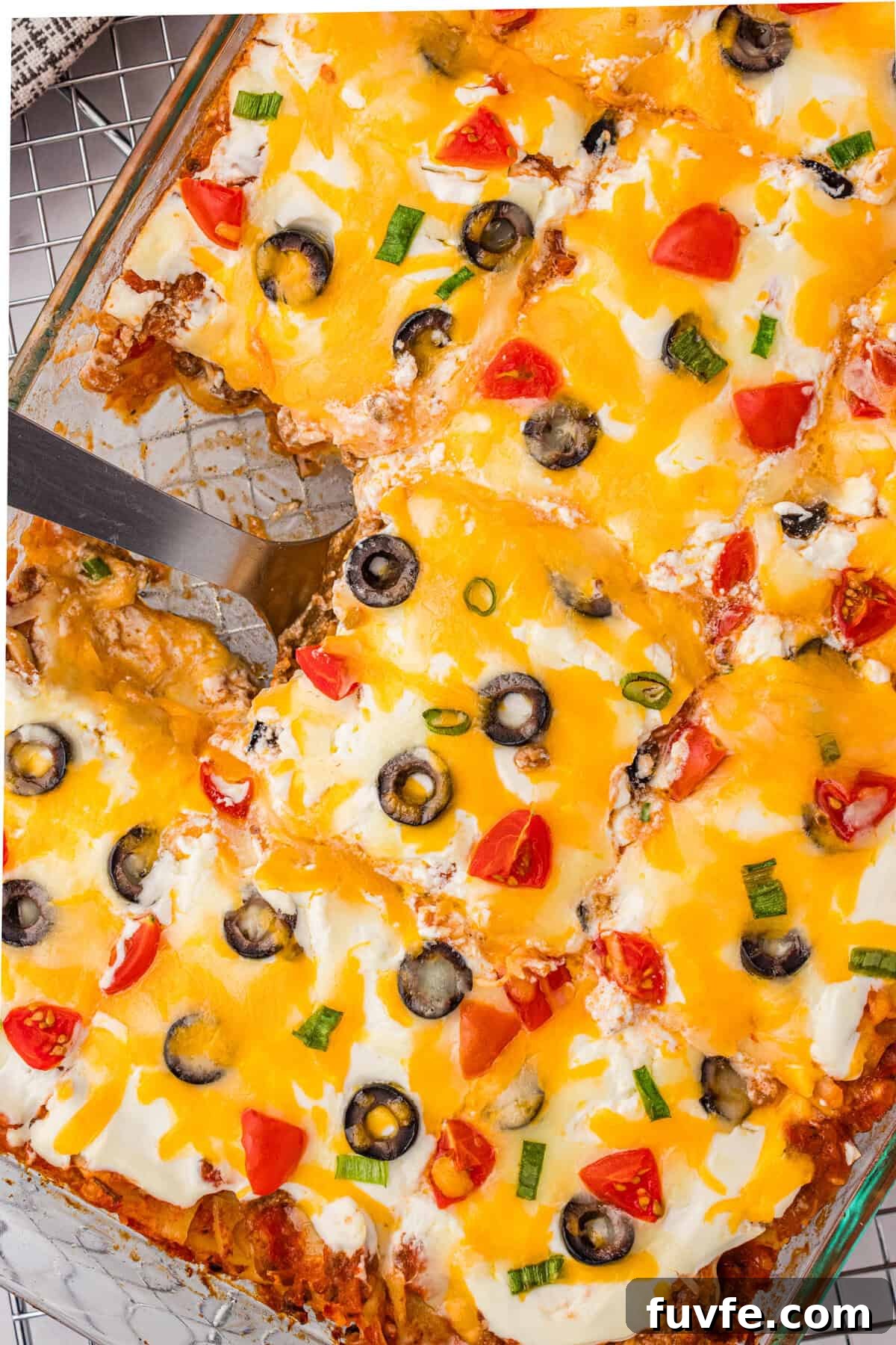 Overhead view of cut taco lasagna in a baking dish with a serving spatula.