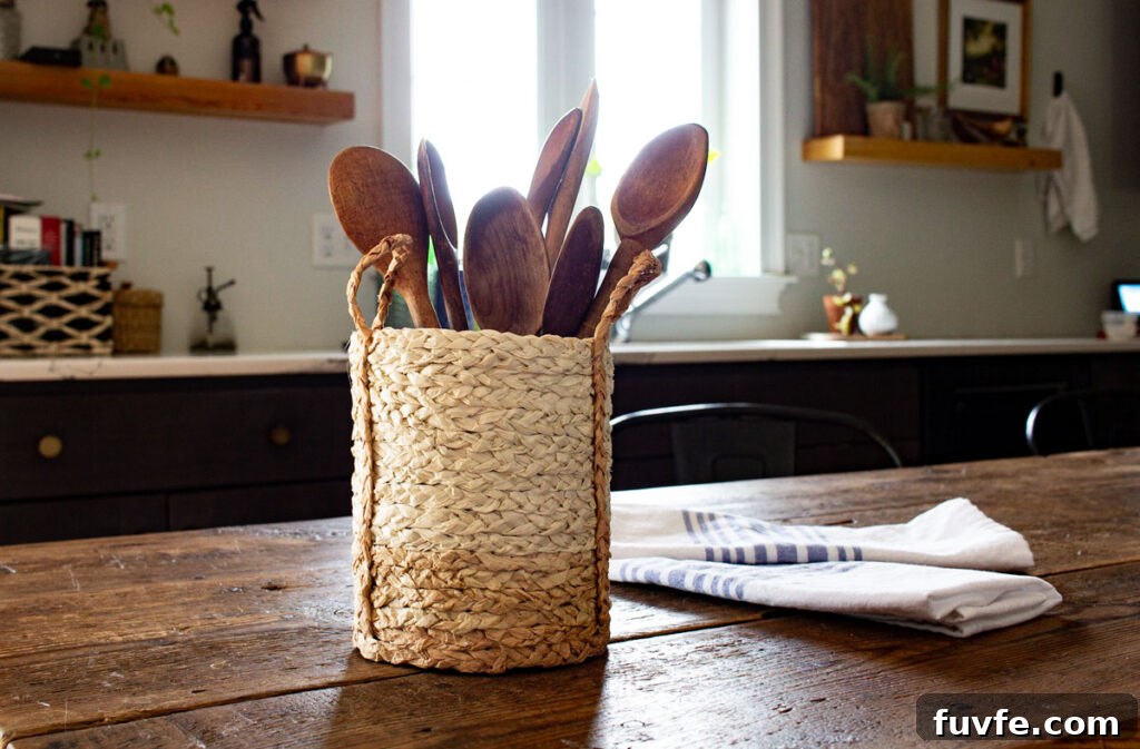 Create a Stunning Ombré Basket: Step-by-Step DIY Guide 11 Here's the finished ombre basket with handles holding a set of vintage wooden spoons on a rustic wood table in the kitchen.