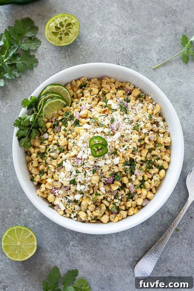 Mexican corn salad in a white bowl with lime and cilantro