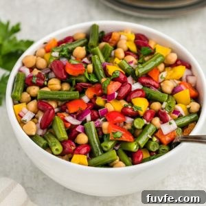 Three bean salad in white bowl with spoon inside