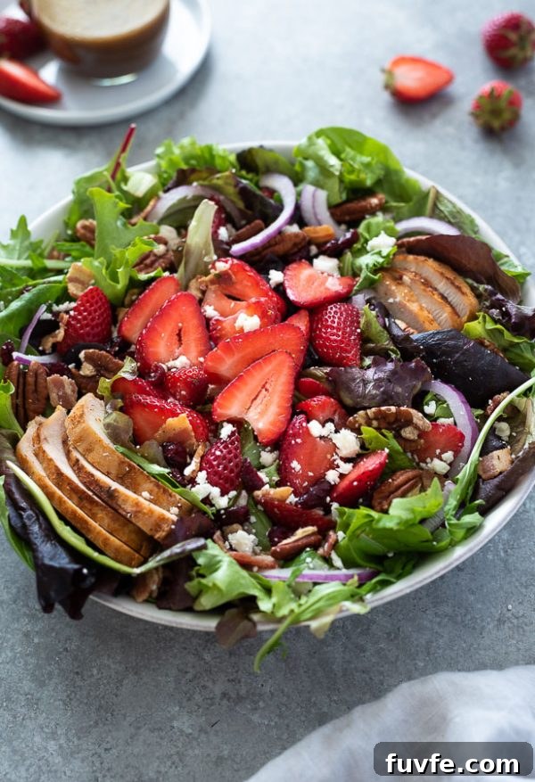 strawberry fields salad in a bowl with sliced strawberries and chicken on top
