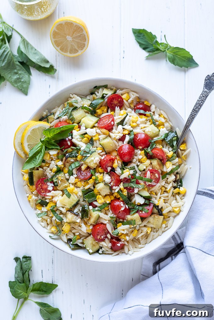 Orzo pasta salad in a bowl with corn, cherry tomatoes and basil