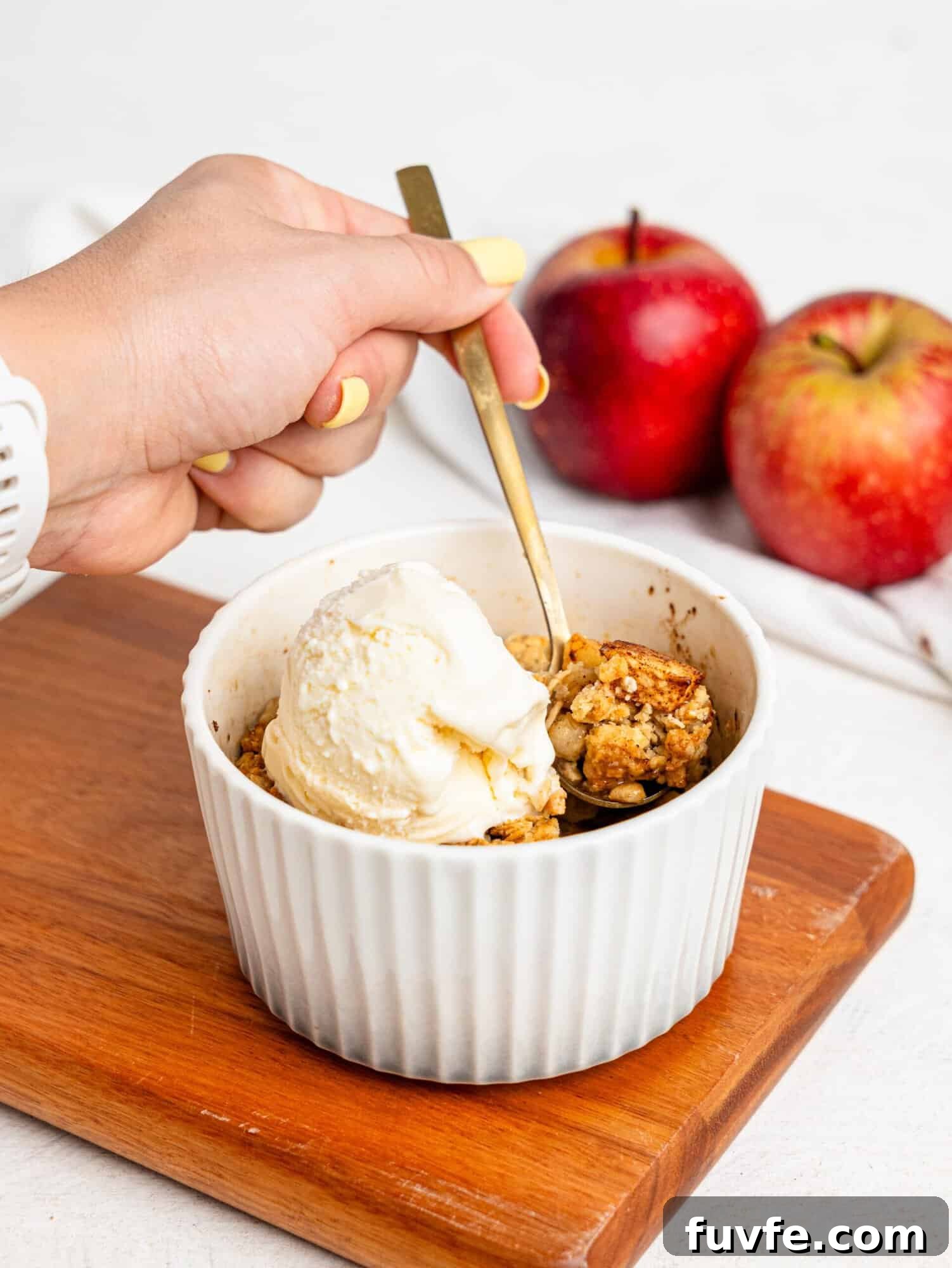 Single Serve Apple Crumble in a small ramekin topped with vanilla ice cream.