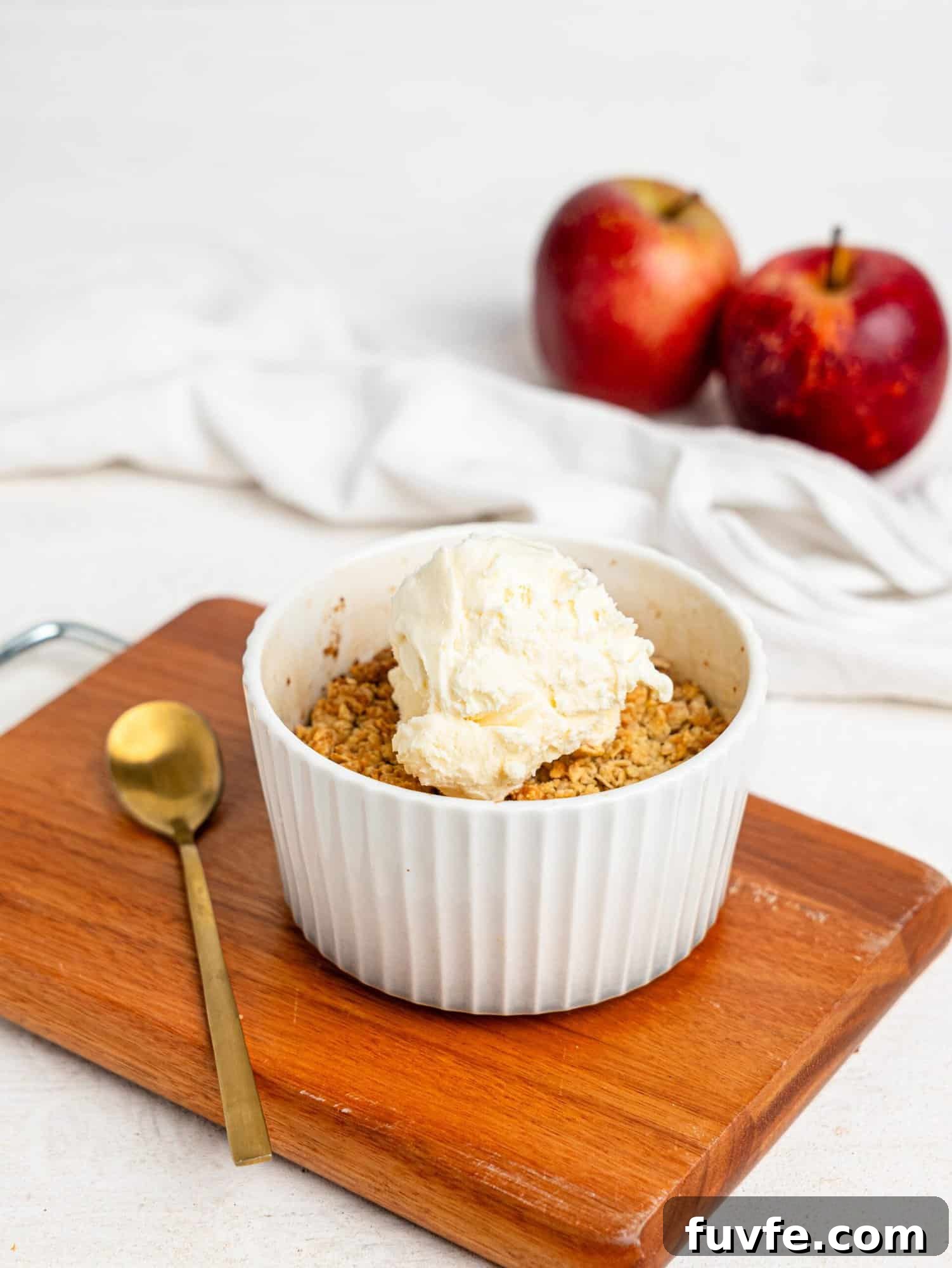 Single Serve Apple Crumble in a small ramekin topped with vanilla ice cream.