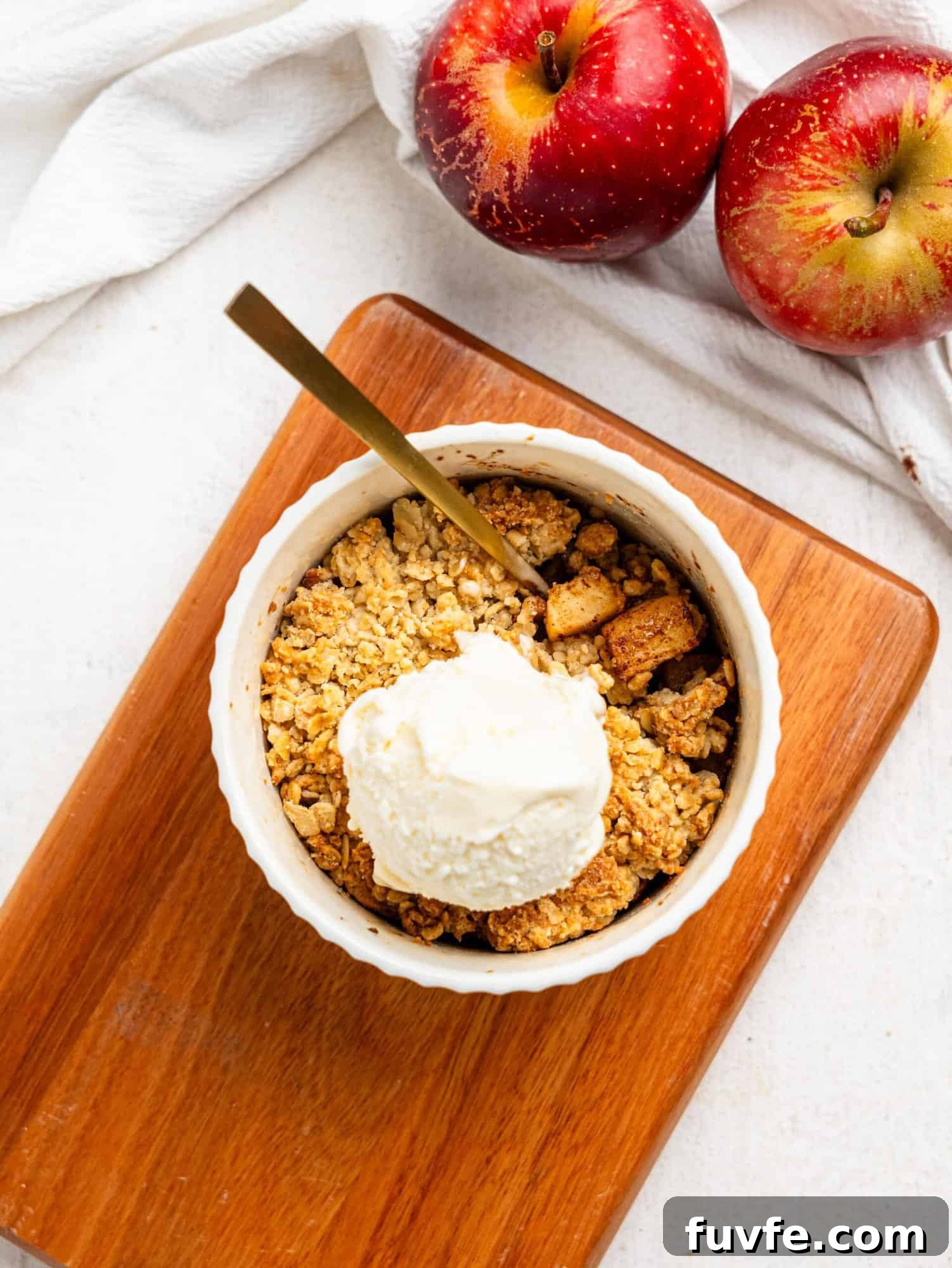 Single Serve Apple Crumble in a small ramekin topped with vanilla ice cream.