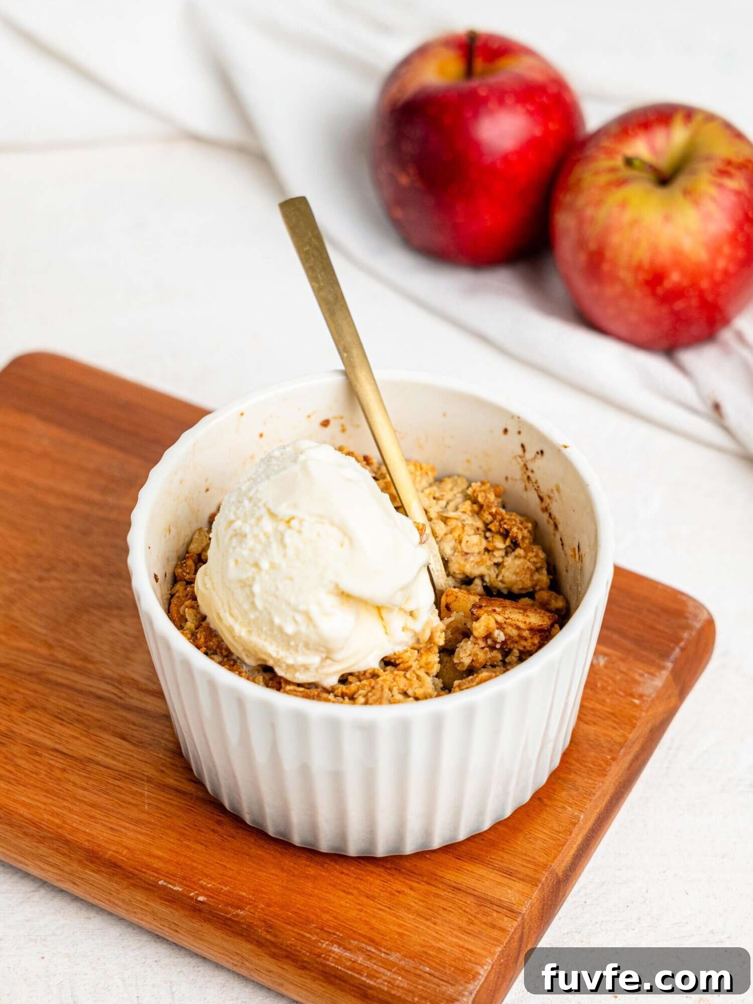 Single Serve Apple Crumble in a small ramekin topped with vanilla ice cream.