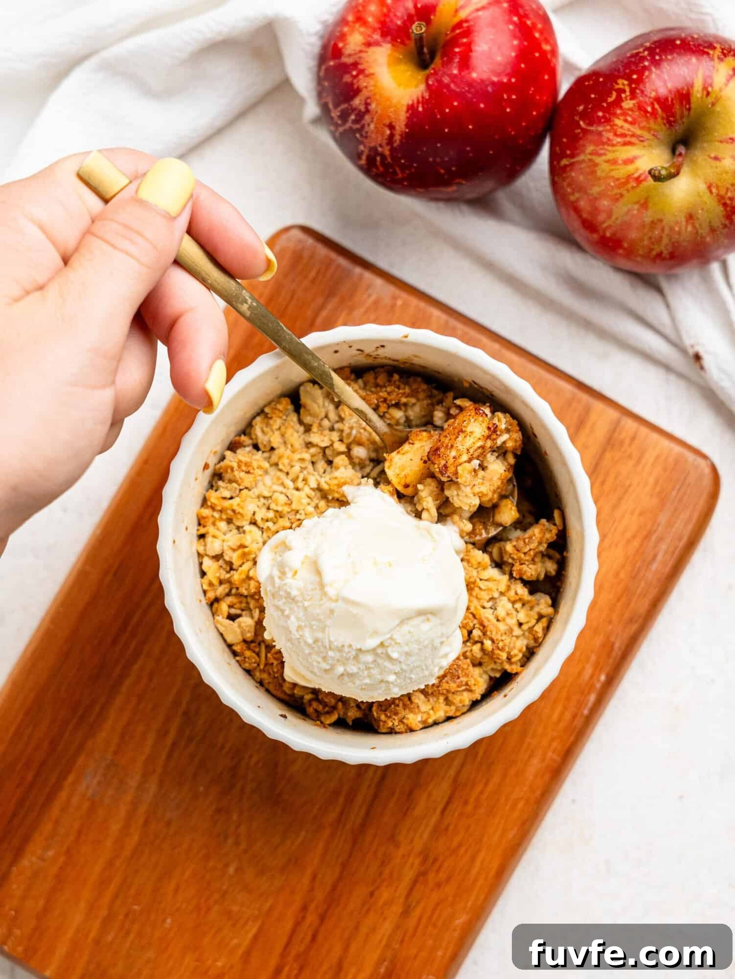 Single Serve Apple Crumble in a small ramekin topped with vanilla ice cream.