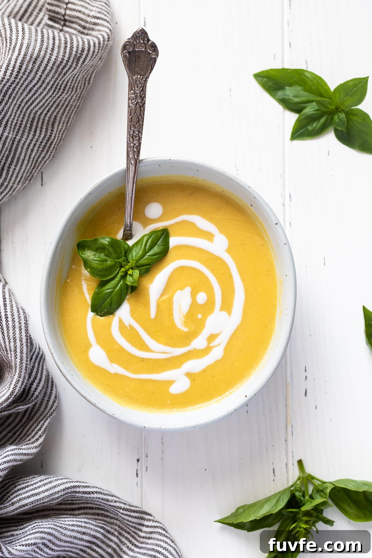 Summer squash soup in white bowl with coconut milk and basil on top