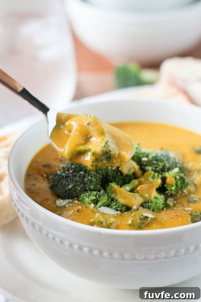 Spoonful of broccoli cheese soup being lifted out of a bowl.