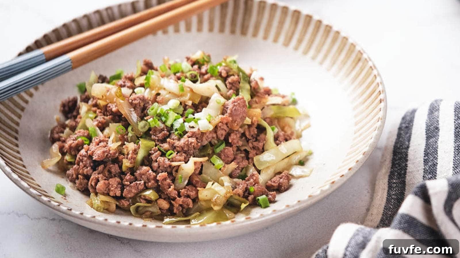 A plate of stir-fried minced meat with chopped green onions and cabbage, served alongside chopsticks on a gray textured surface.