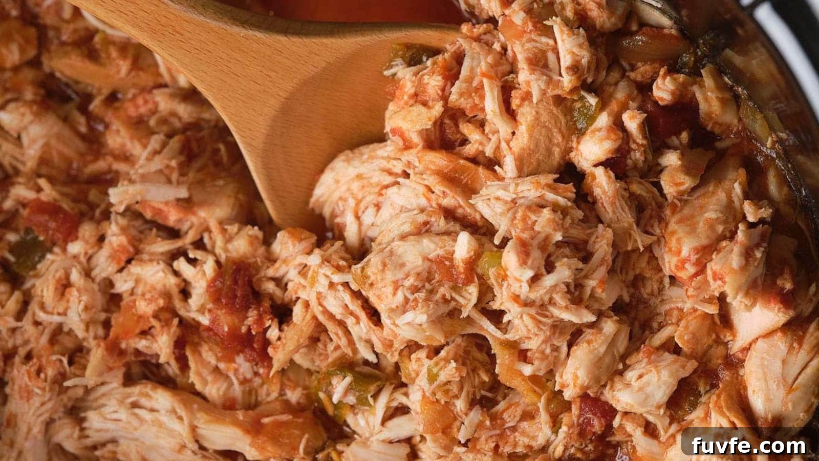 Close-up of shredded chicken mixed with salsa, being stirred with a wooden spoon.