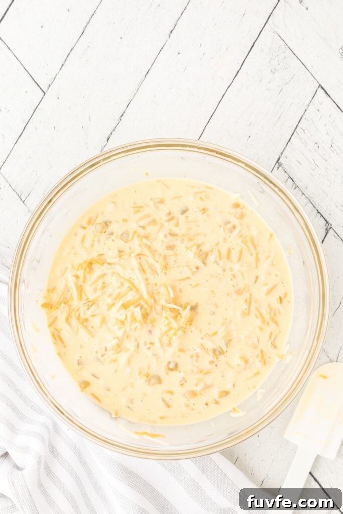 Mixed egg, cheese, and green chili casserole mixture in a glass bowl