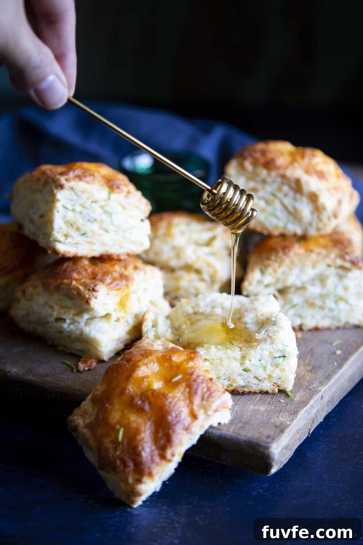 Honey is being drizzled on a biscuit.