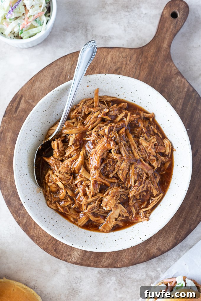 Slow Cooker BBQ Pulled Chicken Sandwiches 3 Bowl of bbq pulled chicken with a spoon