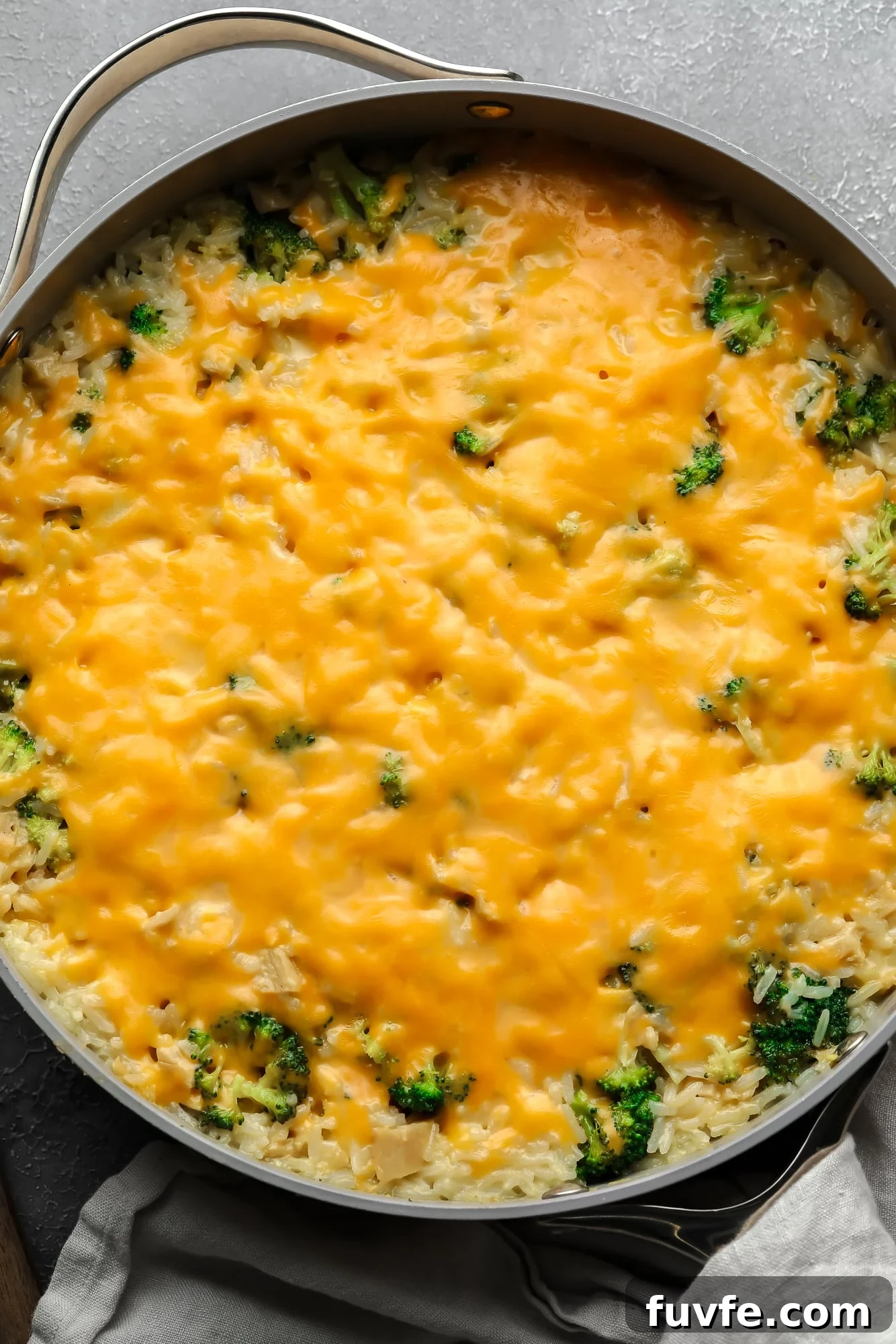 a cheese-covered broccoli and rice vegan casserole in a large skillet.