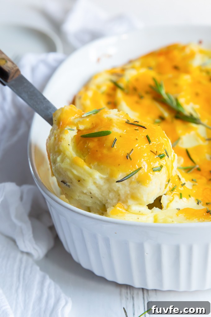 Spoonful of twice baked mashed potatoes lifting out of baking dish