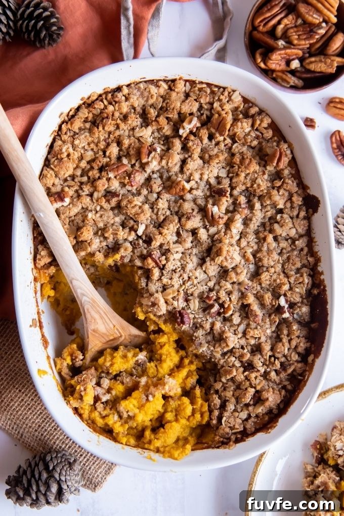 Spoon digging into butternut squash casserole with streusel topping