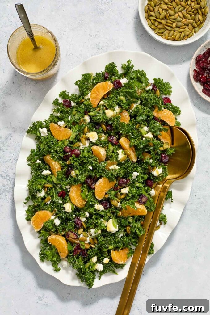 Kale and Orange Salad with Citrus Vinaigrette Recipe 2 Kale salad with goat cheese on a platter with salad servers.