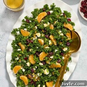 Kale and Orange Salad with Citrus Vinaigrette Recipe 7 Kale salad with goat cheese on a platter with salad servers.