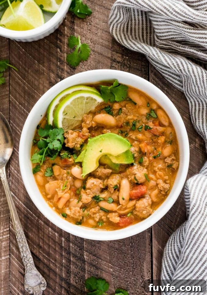 White Bean and Turkey Chili Recipe 4 Bowl of white turkey chili with sliced avocado, cilantro and lime on top.